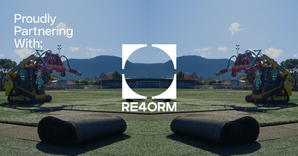 Synthetic turf installation on sports field with machinery and RE4ORM logo, mountains in background