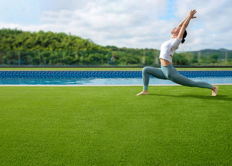 Person practicing yoga on sustainable synthetic grass beside a backyard pool outdoors